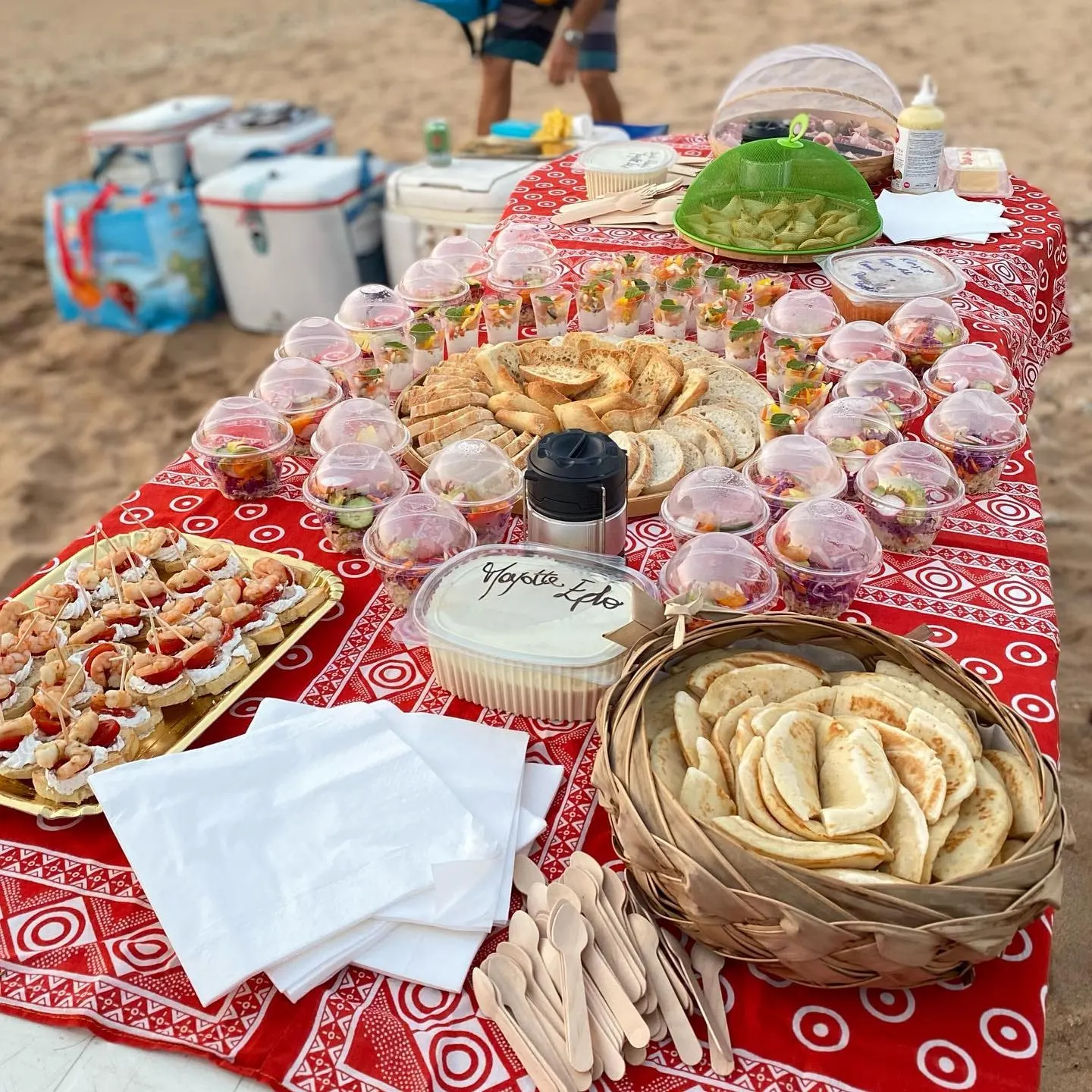 Buffet mahorais sur nappe rouge : crêpes, samossas, beignets et corbeilles de pain