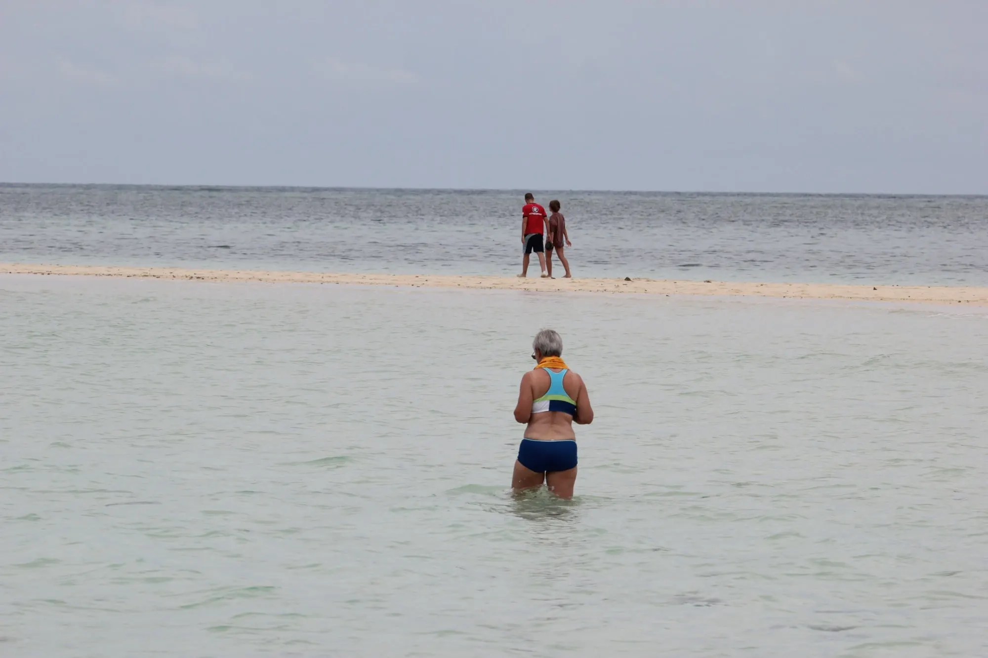 Des passagers marchent dans l’eau peu profonde autour de l’îlot
